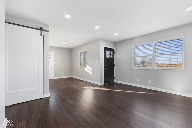 foyer entrance featuring dark hardwood / wood-style flooring, a barn door, and a healthy amount of sunlight