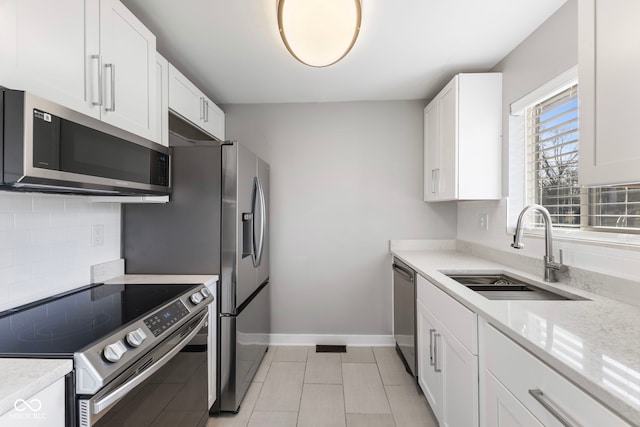 kitchen featuring sink, white cabinetry, stainless steel appliances, tasteful backsplash, and light stone countertops