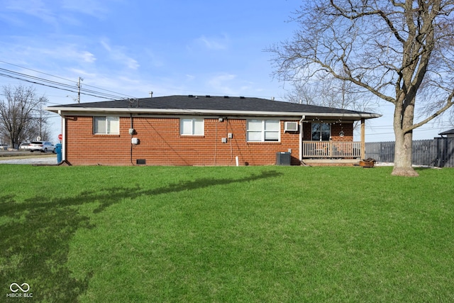 rear view of property with central AC unit, a yard, an AC wall unit, and covered porch