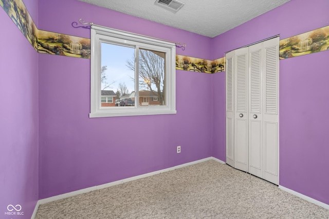 unfurnished bedroom featuring carpet floors, a textured ceiling, and a closet