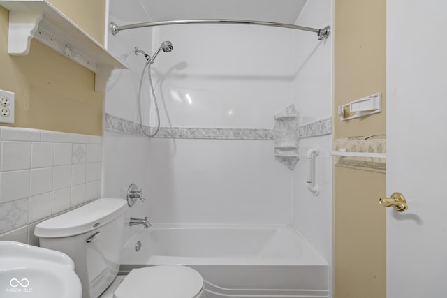 bathroom featuring toilet, bathtub / shower combination, and tile walls