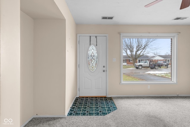 foyer entrance with ceiling fan and carpet flooring