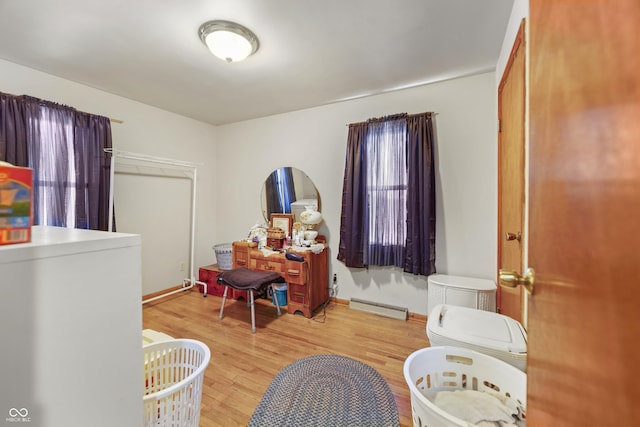 bedroom featuring hardwood / wood-style flooring and a baseboard heating unit