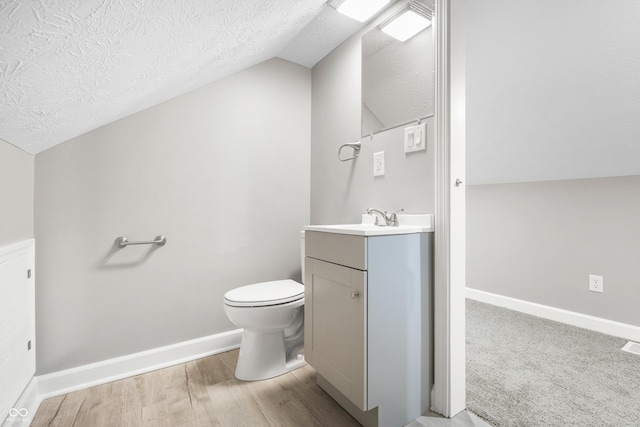 bathroom featuring vanity, vaulted ceiling, a textured ceiling, and toilet