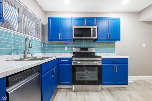 kitchen with sink, light wood-type flooring, blue cabinetry, and appliances with stainless steel finishes