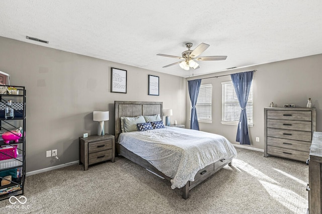 carpeted bedroom featuring ceiling fan and a textured ceiling