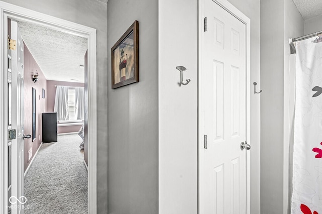 corridor with a textured ceiling and carpet flooring