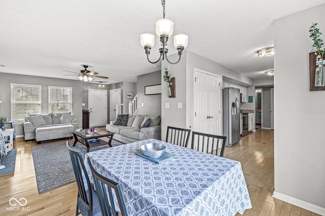 dining area featuring ceiling fan with notable chandelier, a textured ceiling, and light hardwood / wood-style floors