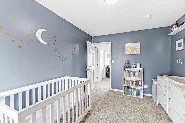 bedroom with light carpet, a nursery area, and a textured ceiling