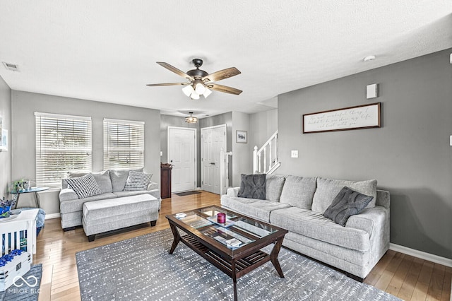 living room with hardwood / wood-style flooring, a textured ceiling, and ceiling fan