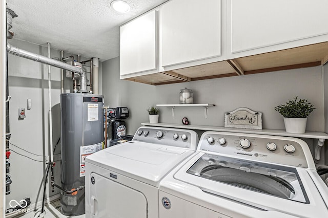 washroom with cabinets, gas water heater, a textured ceiling, and washer and clothes dryer