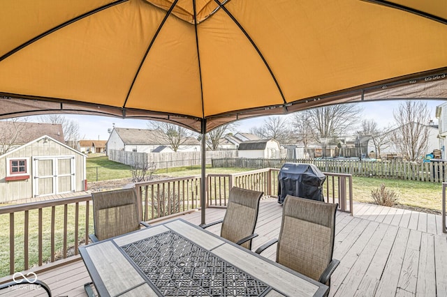 wooden deck with a gazebo, area for grilling, a lawn, and a storage shed