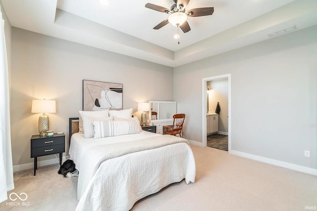 bedroom with ceiling fan, connected bathroom, a raised ceiling, and carpet