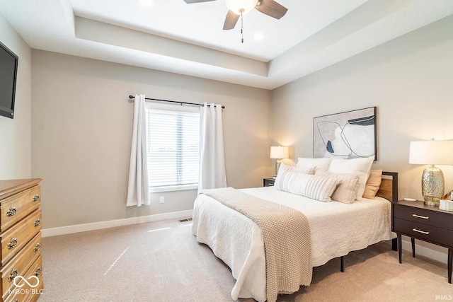 bedroom featuring light carpet, a raised ceiling, and ceiling fan