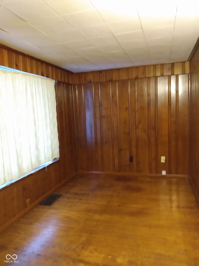 spare room with hardwood / wood-style floors and wood walls