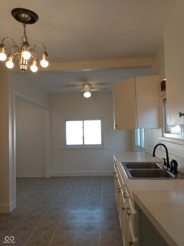 kitchen with ceiling fan with notable chandelier, sink, and pendant lighting