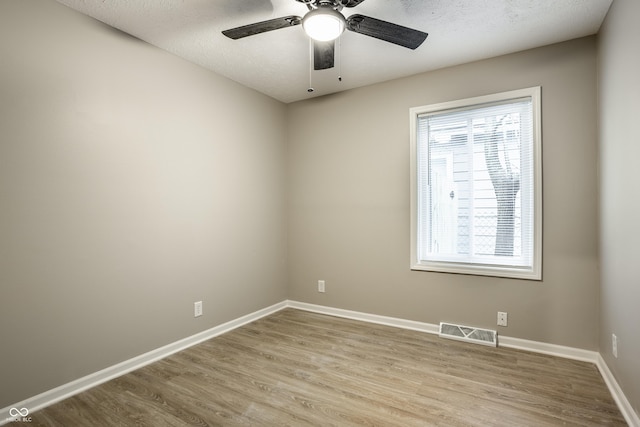 empty room with ceiling fan, a textured ceiling, and light hardwood / wood-style floors