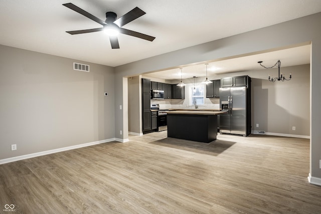 kitchen featuring pendant lighting, light wood-type flooring, a center island, and appliances with stainless steel finishes