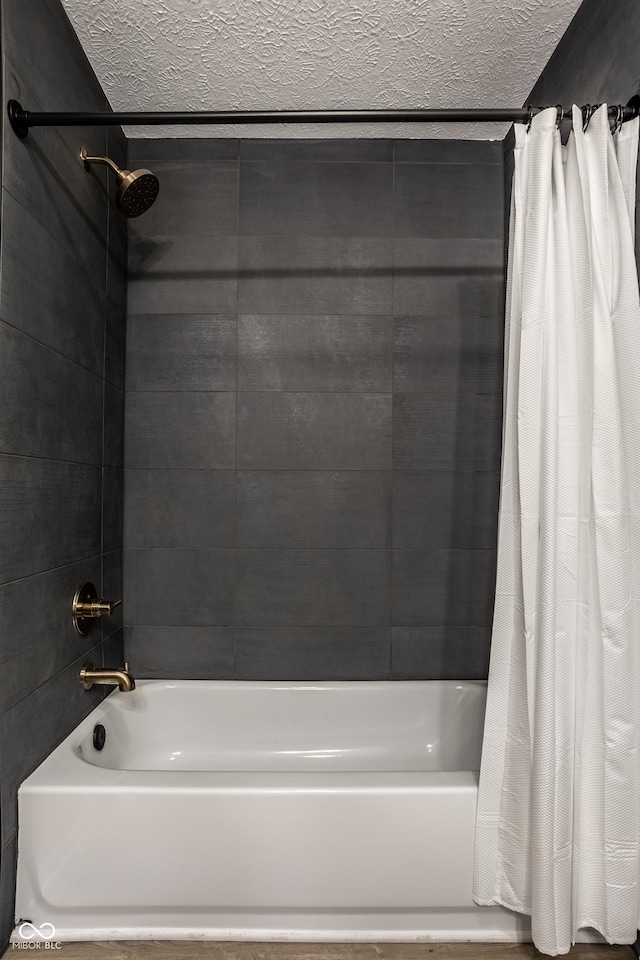 bathroom with shower / bathtub combination with curtain and a textured ceiling