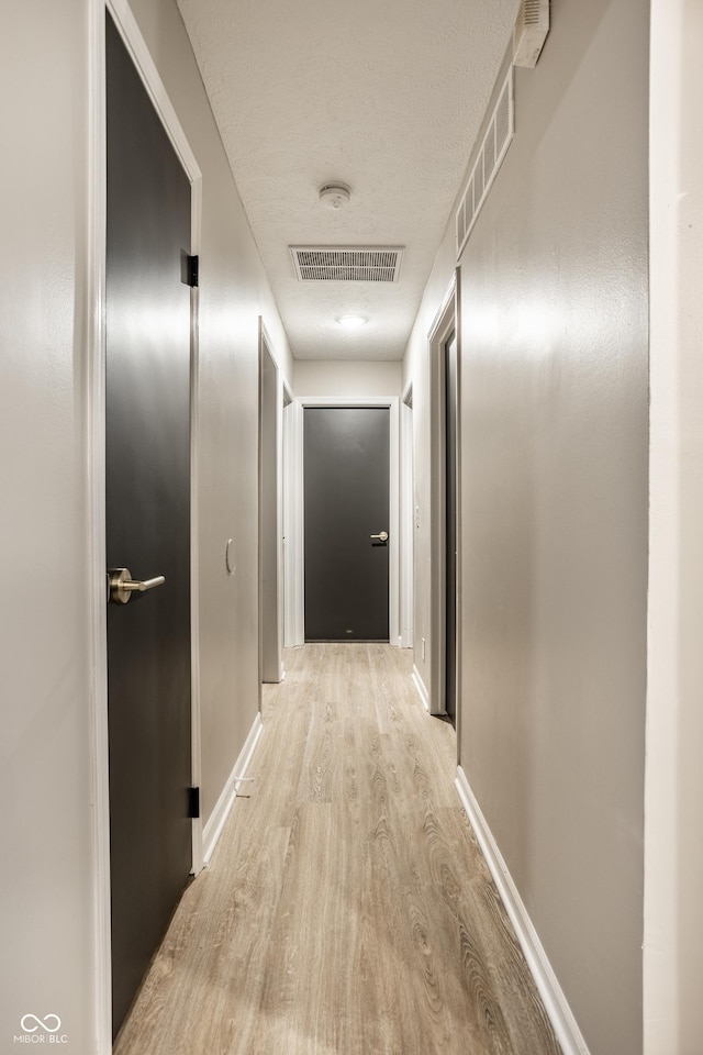 corridor featuring a textured ceiling and light wood-type flooring