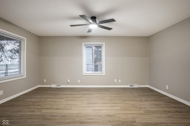 empty room with hardwood / wood-style flooring, a textured ceiling, and ceiling fan