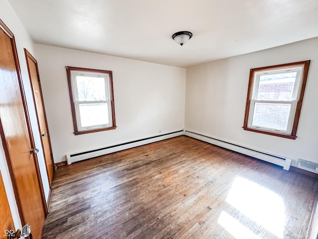 spare room with dark wood-type flooring, a wealth of natural light, and baseboard heating