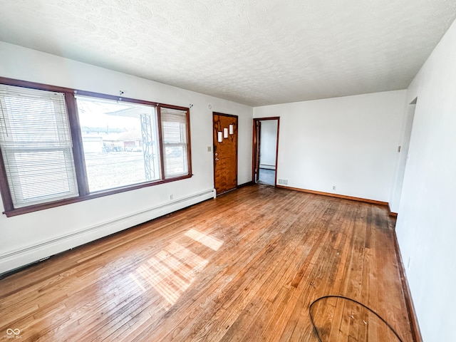 empty room with hardwood / wood-style floors, a textured ceiling, and a baseboard heating unit