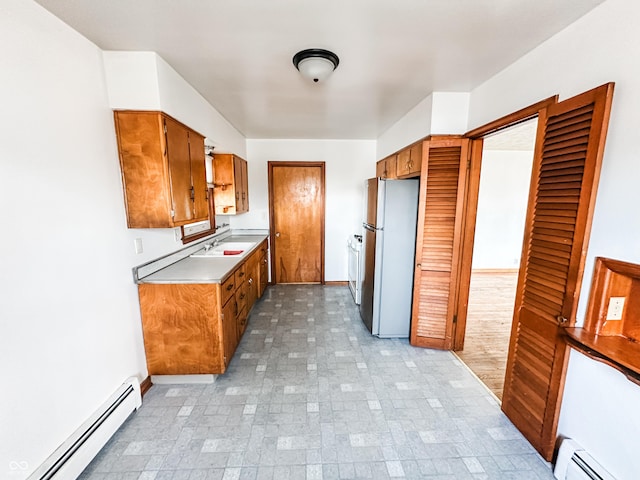 kitchen with a baseboard heating unit, sink, and stainless steel refrigerator