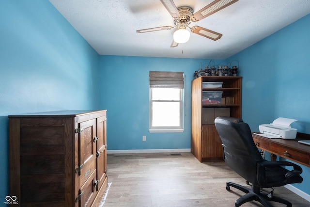 home office featuring ceiling fan, light wood finished floors, a textured ceiling, and baseboards