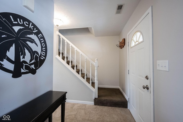 foyer featuring baseboards, stairs, and visible vents