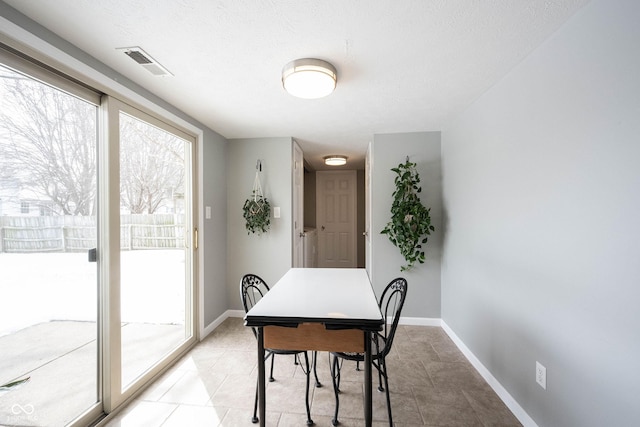 dining room with baseboards, visible vents, and a textured ceiling