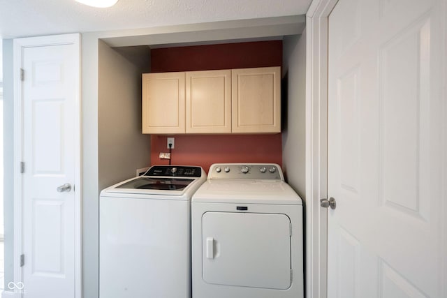 clothes washing area featuring cabinet space and washer and clothes dryer