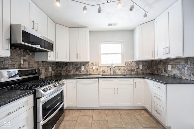 kitchen with stainless steel appliances, a sink, visible vents, white cabinetry, and decorative backsplash