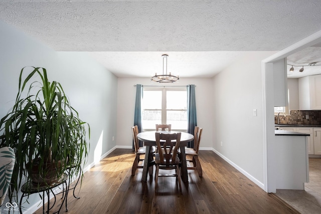 dining space with dark wood-style floors, baseboards, and a notable chandelier