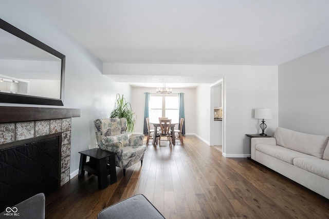 living room with dark wood-style floors, a fireplace, baseboards, and an inviting chandelier