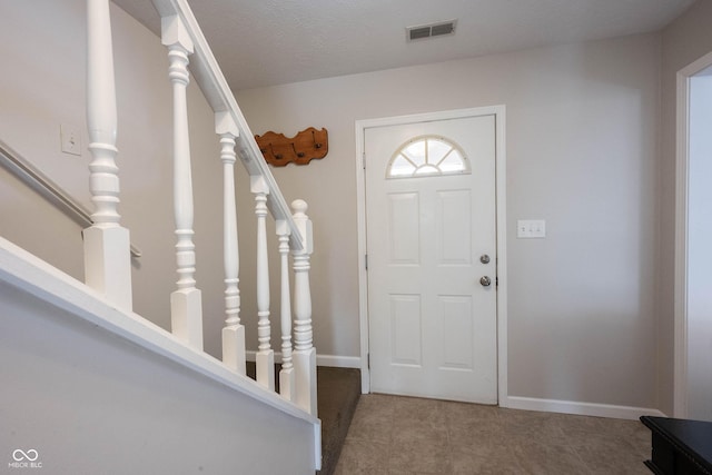 entryway with stairs, visible vents, and baseboards