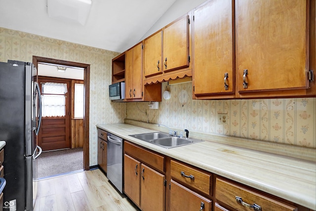 kitchen with sink, vaulted ceiling, stainless steel appliances, and light hardwood / wood-style floors