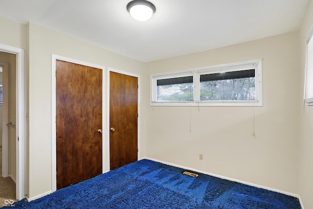 unfurnished bedroom featuring multiple closets and carpet