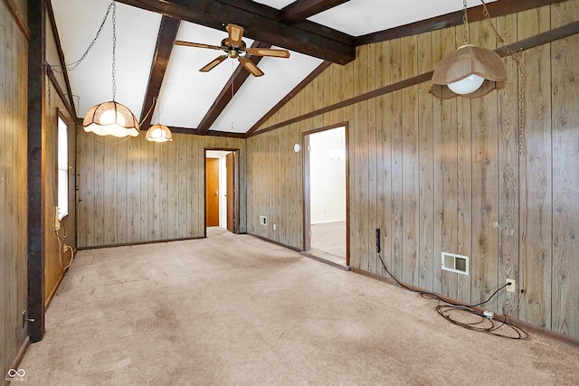 carpeted spare room with lofted ceiling with beams, ceiling fan, and wooden walls