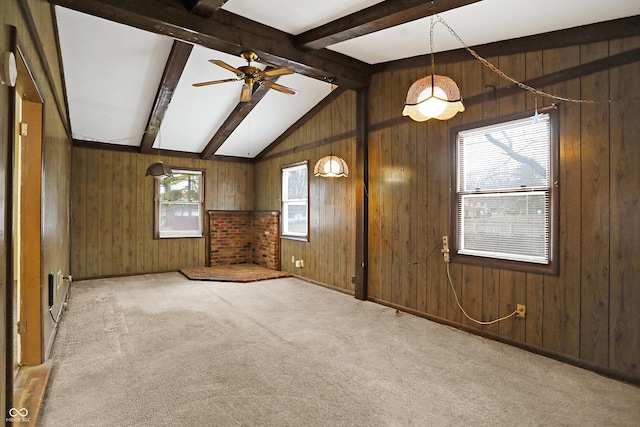 carpeted spare room featuring lofted ceiling with beams, ceiling fan, and wooden walls