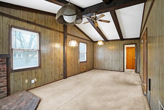 carpeted spare room with vaulted ceiling with beams, ceiling fan, and wood walls