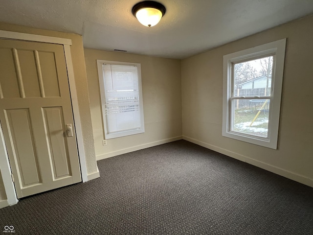 carpeted empty room featuring a textured ceiling