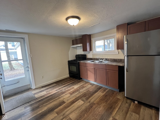 kitchen featuring sink, dark wood-type flooring, stainless steel refrigerator, gas stove, and a textured ceiling