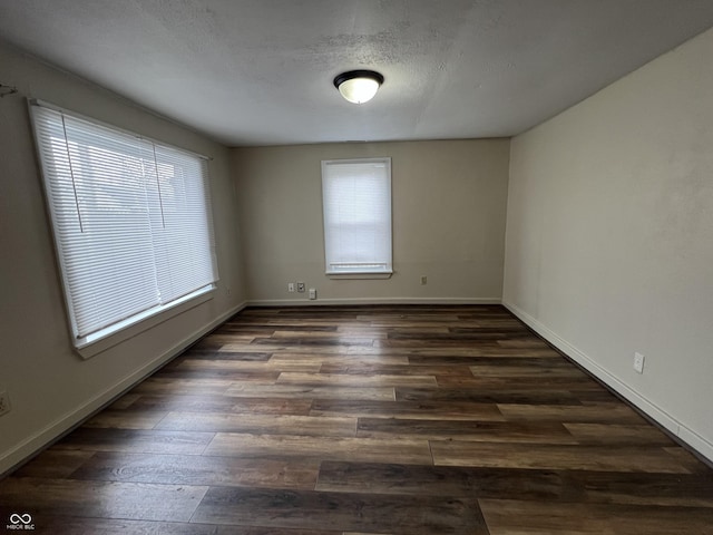 empty room with dark wood-type flooring and a textured ceiling