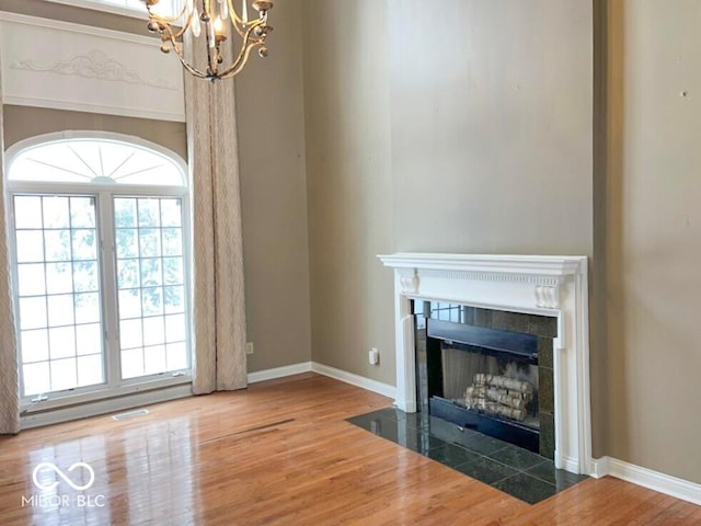 unfurnished living room featuring a notable chandelier and hardwood / wood-style flooring