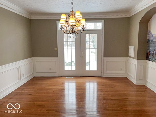 unfurnished dining area with a notable chandelier, light hardwood / wood-style flooring, french doors, and a textured ceiling