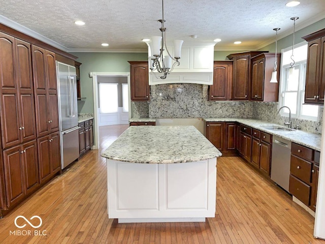 kitchen with sink, a center island, hanging light fixtures, light hardwood / wood-style flooring, and appliances with stainless steel finishes