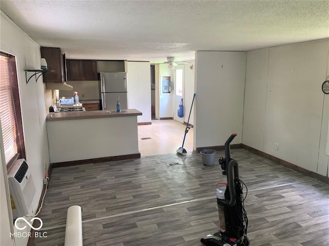 kitchen with dark wood-type flooring, dark brown cabinets, stainless steel refrigerator, and a textured ceiling