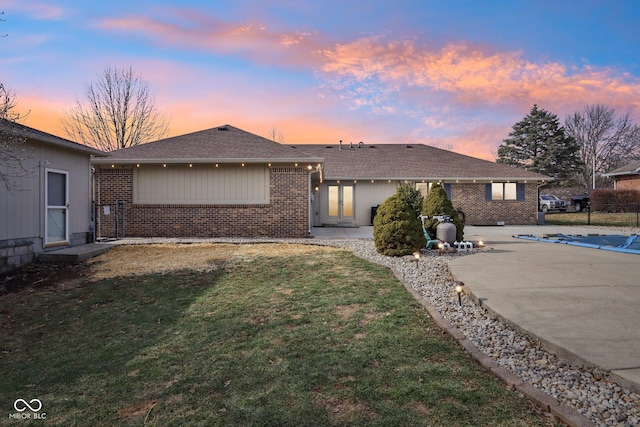 ranch-style home with a lawn and a patio