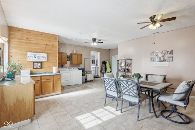 dining area featuring ceiling fan, washing machine and clothes dryer, and wooden walls